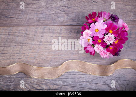 Ein Bouquet von rosa und lila Blumen cosmea oder Cosmos mit Band auf rustikalen hölzernen Brettern. Kopieren Sie Platz. Mutter, Valentines, Frauen, Hochzeit conc Stockfoto