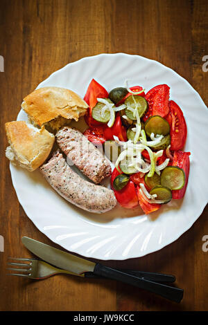 Weißwurst mit Gurke, Tomate, Zwiebel Salat und frische Roll Stockfoto