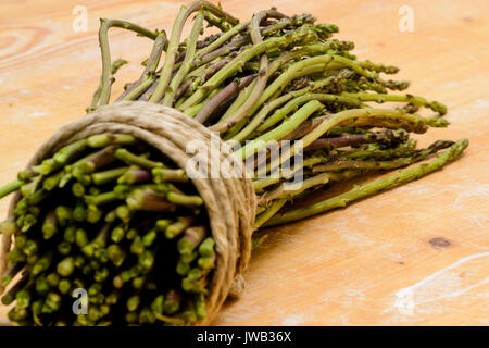 Ein Bündel Spargel mit einer Schnur auf einer hölzernen Schneidebrett gebunden. Close up Querformat. Stockfoto