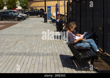 Besucher sitzen und auf Bänken mit Blick auf den Fluss Lagan an saniert von Belfast dockland an der Donegall Quay entspannen Stockfoto