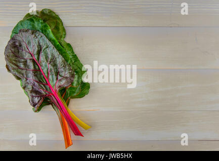 Stapel von Rainbow Mangold mit Kopie Raum nach rechts über Holz- table top Stockfoto