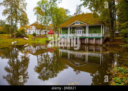 Blick auf einen Teich und grünes Holzhaus und zwei Pavillons mit Spiegelung im Wasser. Palmse Manor, Estland Stockfoto