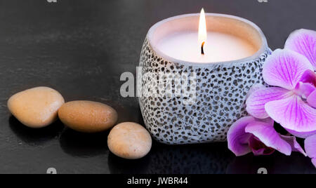 Spa Kerze mit Massage Steine und orchid flower Stockfoto