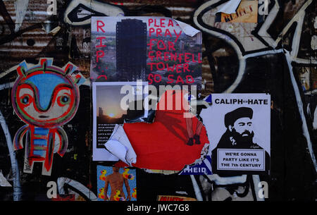 Ein Poster zum Ausdruck Trauer für die Opfer von Grenfell Turm unter den Graffiti an einer Wand in der Brick Lane, im East End von London Stockfoto