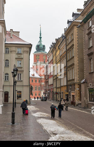 Warschau, Polen - 16 Januar, 2017: unbekannte Menschen entlang der Swietojanska Strasse mit roayl Schloss Clock Tower in der Altstadt. Warschau ist die Hauptstadt Stockfoto