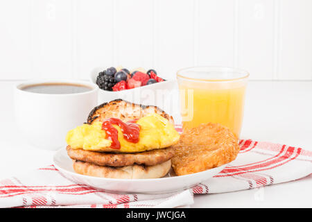 Breakfast Sandwich mit frischem Obst, Kaffee und Saft serviert. Stockfoto