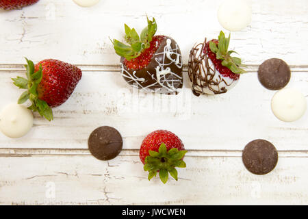 Frische reife Erdbeeren und Schokolade getauchte Beeren und Schokolade Wafer auf rustikale Holzplanken. Stockfoto