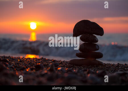 Silhouette einer rock Cairn am Strand von Lake Superior bei Sonnenuntergang gestapelt. Stockfoto