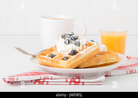 Teller mit frischen Waffeln mit Blaubeeren, Kaffee und Saft. Stockfoto