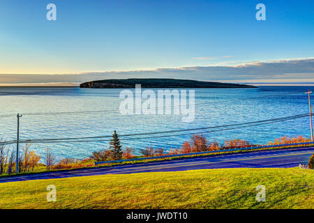 Die Insel Bonaventure während Sunrise in Gaspe Halbinsel, Quebec, Kanada, Gaspesie Region mit blauen Wasser und beleuchtete Gras Stockfoto