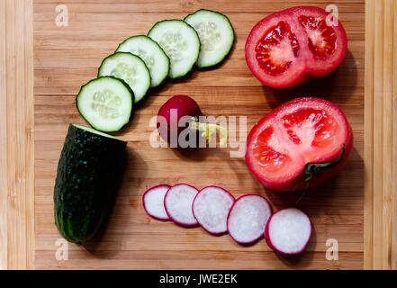 Gemüse, Gurken, Radieschen und Tomaten sind in Ringe schneiden. Stockfoto