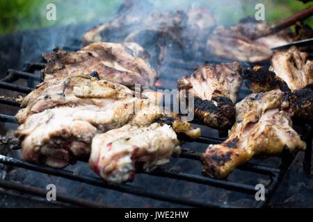 Eine duftende, aber ein wenig mehr nicht bereit Grill vom Huhn Beine und Schenkel. Es wird auf offenem Feuer und Rauch im Hof im Dorf vorbereitet. Stockfoto