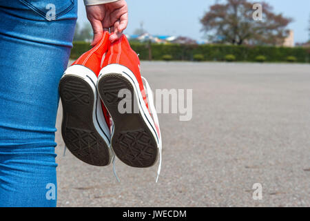 Frau hand mit einem roten Sneaker mit Platz für Text oder Symbol. Stockfoto