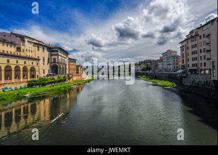 Eine einzelne scull bewegt sich entlang des Arno Flusses unter einem dramatischen Sommerhimmel Stockfoto