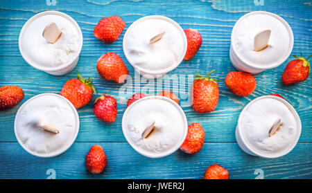 Eis und Erdbeeren auf einem blauen Hintergrund Holz. Sommer Hintergründe. Stockfoto