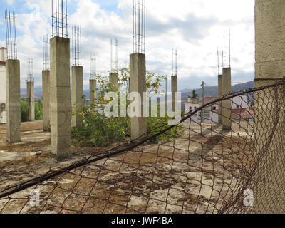 Stillgelegte Baustelle mit hohen Stahlbeton Säulen hinter verrosteten Zaun Stockfoto