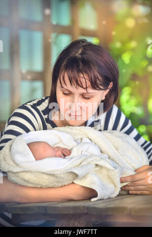 Liebevolle Mutter beugt sich über das Baby. Sommer Porträt im Garten Stockfoto