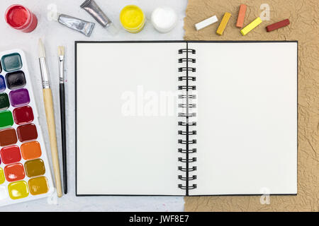 Öffnen Skizzenbuch für Kunstwerk mit Aquarellfarben, Palette, Pastell und Pinseln. künstlerische Arbeit tools. Blick von oben. Stockfoto