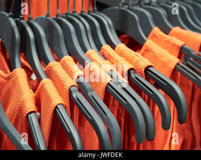 Orange Kleider auf Kleiderbügeln im Store. Stockfoto