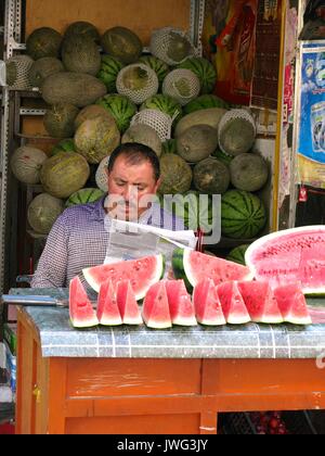 Wassermelone Verkäufer lesen Zeitung in Urumqi Alter Markt Stockfoto