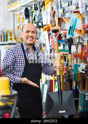 Professionelle senior Verkäufer mit Garten Werkzeuge in Gebäude store Stockfoto