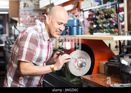 Ältere Arbeiter nachschärfen Messer interlock Spirale Rad system Maschine in der Werkstatt Stockfoto