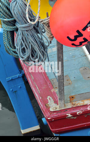 Bunte Fischerboote und Rettungsringe mit Fischen schwimmt und Netze in der Nähe upd der Decks und Ausrüstung schwimmt Kabel Netze und Boote Namen Planken und Rümpfe Stockfoto