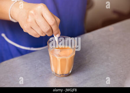 Hot Thai Kaffee Milch Hand halten Löffel brauen gemischt Signatur lokale Getränke Stockfoto