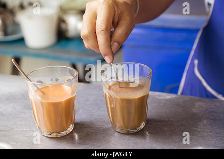 Hot Thai Kaffee Milch Hand halten Löffel brauen gemischt Signatur lokale Getränke Stockfoto