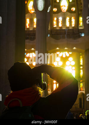 Ein Tourist ist, die Bilder von den lackierten Fenster der Westfassade der Kathedrale Sagrada Familia in Barcelona. Die noch unfertige Wahrzeichen von Stockfoto