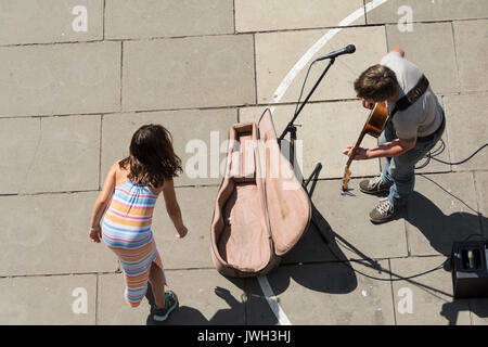 Ein junges Mädchen gibt ein strassenmusikant etwas Geld in London, Großbritannien Stockfoto