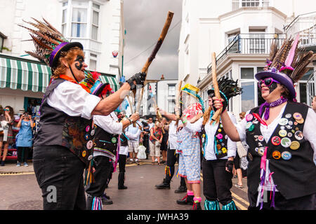 England, Broadstairs folk Woche. Dead Horse und die Broomdashers Morris Seite, regionalen Stil der traditionellen Englischen Morris Dance, Tanzen auf der Straße. Geschwärzte Gesichter und das Tragen von Mützen mit Federn. Stockfoto