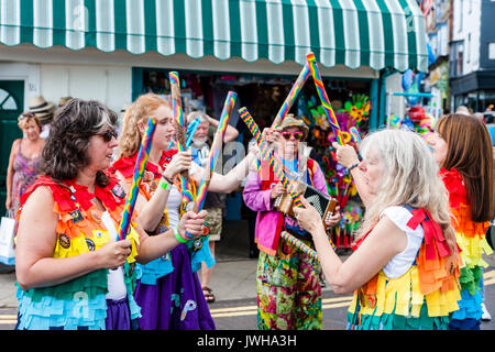 Jährliche Broadstairs Folk Woche Festival. Volkstänzer, Lose Frauen Morris Seite tanzen auf der Straße und halten Holz hell farbigen Pole. Tragen rainbow tatter Jacken. Stockfoto