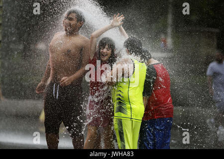 Chicago, USA. 11 Aug, 2017. Menschen spielen bei der Crown Fountain in Millennium Park in der Innenstadt von Chicago, USA, am 12.08.11, 2017. Crown Fountain ist ein interaktiver Arbeit der öffentlichen Kunst und video Skulptur in Chicago, Millennium Park vorhanden. Der Brunnen besteht aus schwarzem Granit einen reflektierenden Pool zwischen ein paar Glasbaustein Türme mit LED-Display digitale Videos auf Ihr inneres Gesicht zu zeigen. Credit: Wang Ping/Xinhua/Alamy leben Nachrichten Stockfoto