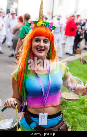 Sehr glückliche junge Frau, 20s, das Tragen von Rainbow top und orange Haare. Bis bubble Aerosol blasen, und in der anderen Hand Sammlung Schaufel für die broadstairs Folk Woche Festival. Stellt für Bild, close-up. Auge - Vertrag. Stockfoto
