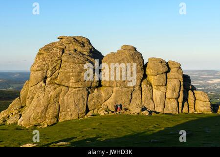 Haytor, Dartmoor, Devon, Großbritannien. 12. August 2017. UK Wetter. Es sind zwei Personen durch die MASIVEN Felsen von Haytor im darmoor Nationalpark, Devon, die in warmen Abend Sonnenschein ist in den Schatten gestellt. Photo Credit: Graham Jagd-/Alamy leben Nachrichten Stockfoto