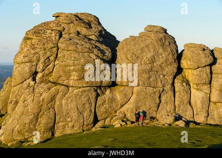 Haytor, Dartmoor, Devon, Großbritannien. 12. August 2017. UK Wetter. Es sind zwei Personen durch die MASIVEN Felsen von Haytor im darmoor Nationalpark, Devon, die in warmen Abend Sonnenschein ist in den Schatten gestellt. Photo Credit: Graham Jagd-/Alamy leben Nachrichten Stockfoto