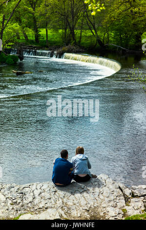 Junges Paar auf einem Felsen mit Blick auf die Horseshoe Falls in Llangollen sitzen Stockfoto