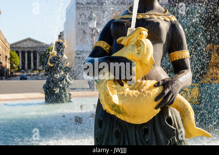 Nahaufnahme des Wasserbrunnens auf dem Concorde-Platz in Paris mit einer Statue eines Nereid, der einen goldenen Fisch hält, der Wasser nach oben spuckt. Stockfoto