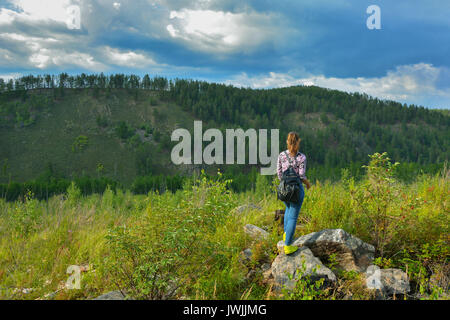 Junge Frau steht auf dem Stein, die Aussicht genießen. Blick von der Rückseite. Wanderlust Travel Concept Stockfoto