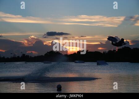 Wake Boarder auf der See bei Sonnenuntergang und hinter einer Wolke aus Wassernebel Stockfoto