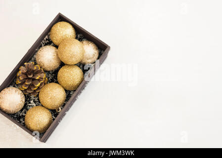 Goldene Weihnachtskugeln in einem Verschlag auf einem weißen Holzmöbeln im Landhausstil Hintergrund. Ansicht von oben Stockfoto