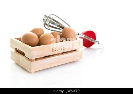 Eier in eine Holzkiste mit alten roten ei Schneebesen auf weißem Hintergrund Stockfoto