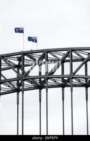 Sydney Harbour Bridge Kletterer und die Australische Flaggen Fliegen an einem windigen Winter Stockfoto