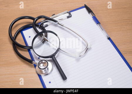 Ansicht von oben von schwarz und silber Metall stethescope und Stift auf leere Notizen auf Blau Clip Board Stockfoto