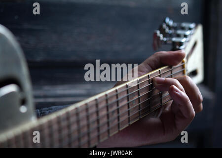 Finger spielen akustische Gitarre auf schwarzem Hintergrund aus dunklem Holz mit selektiven Fokus Stockfoto