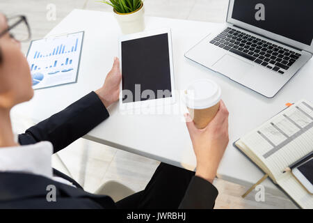 Über die Schulter sehen zuversichtlich white collar worker genießen duftenden Kaffee während der Vorbereitung Jahresabschluss auf digitalen Tablet Stockfoto