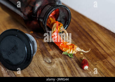 Getrocknete Chilis in einer Flasche auf einem Holz Schneidebrett Stockfoto