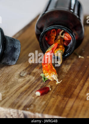 Getrocknete Chilis in einer Flasche auf einem Holz Schneidebrett Stockfoto