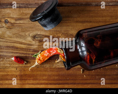 Getrocknete Chilis in einer Flasche auf einem Holz Schneidebrett Stockfoto